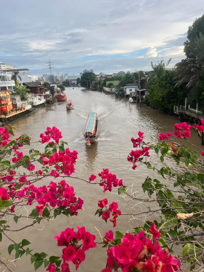 Tourists on a longtail boat in a narrow Bangkok canal surrounded by tropical trees on a combined longtail boat and tuk-tuk tour in Bangkok