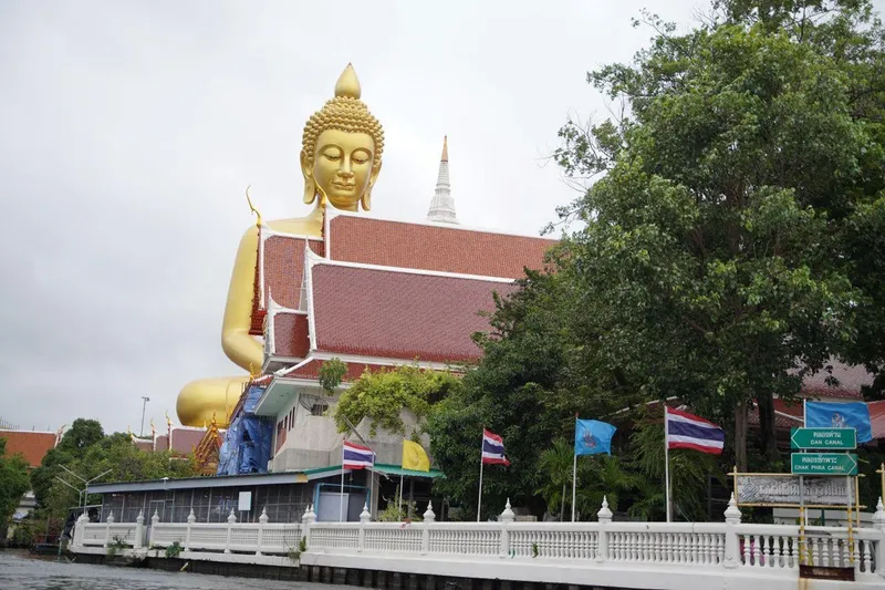 Traditional teak boat on the Chao Phraya River approaching Wat Arun Temple of Dawn on a Bangkok canal tour