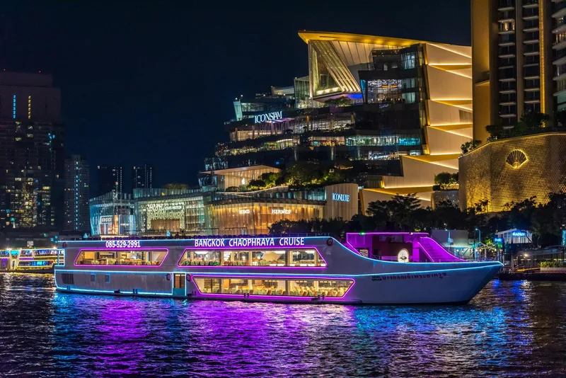 Luxury cruise ship on the Chao Phraya River at night with Bangkok's illuminated skyline and Wat Arun in the background on a bangkok boat tour