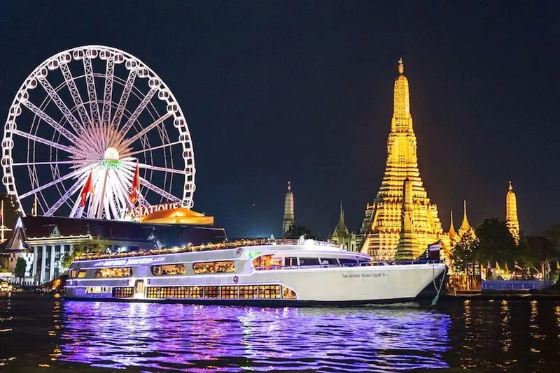 Passengers dining on the White Orchid dinner cruise boat on the Chao Phraya River with Bangkok's illuminated skyline on a bangkok night boat tour