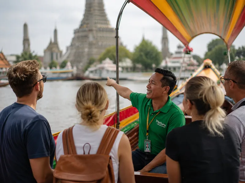 Wat Arun Temple of Dawn seen from a traditional teak boat on the Chao Phraya River on a Bangkok canal tour