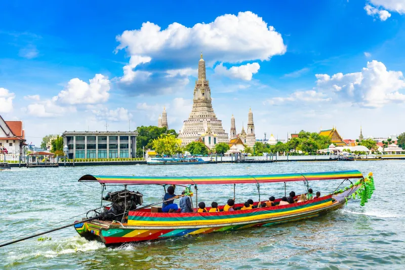 Private longtail boat navigating a quiet residential Bangkok canal flanked by wooden stilt houses on a local life canal tour